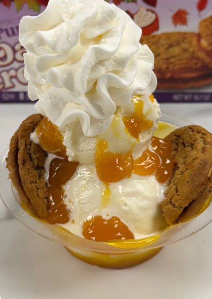 The Pumpkin Creme Pie Sundae: scoops with an orange drizzle under a tall swirl of whipped cream, with a creme pie cookie on each side